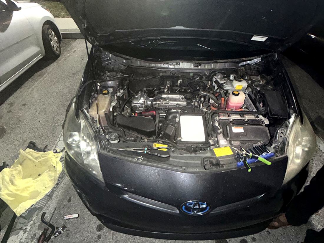 Car with the hood up and fender covers fitted during a mobile repair