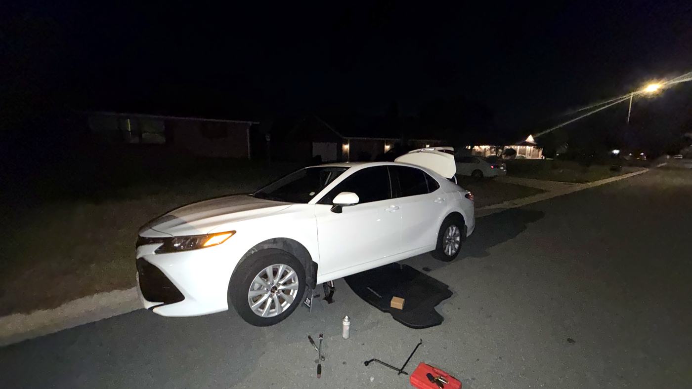 Roadside battery service on a sedan at night in a Tampa parking lot